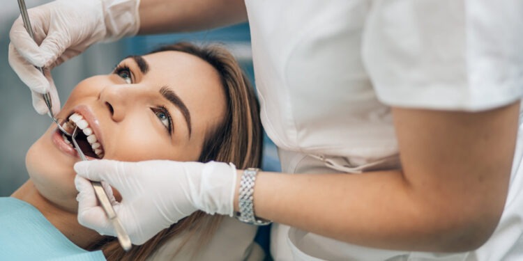 portrait of young blond good-looking woman on dental examination, treating teeth in professional orthodontic clinic