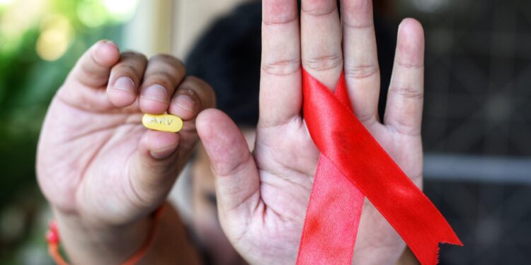 fita vermelha na mão, simbolo de hiv e aids