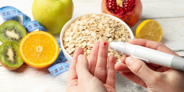 Pessoa medindo glicose no dedo com alimentos saudáveis ao redor.