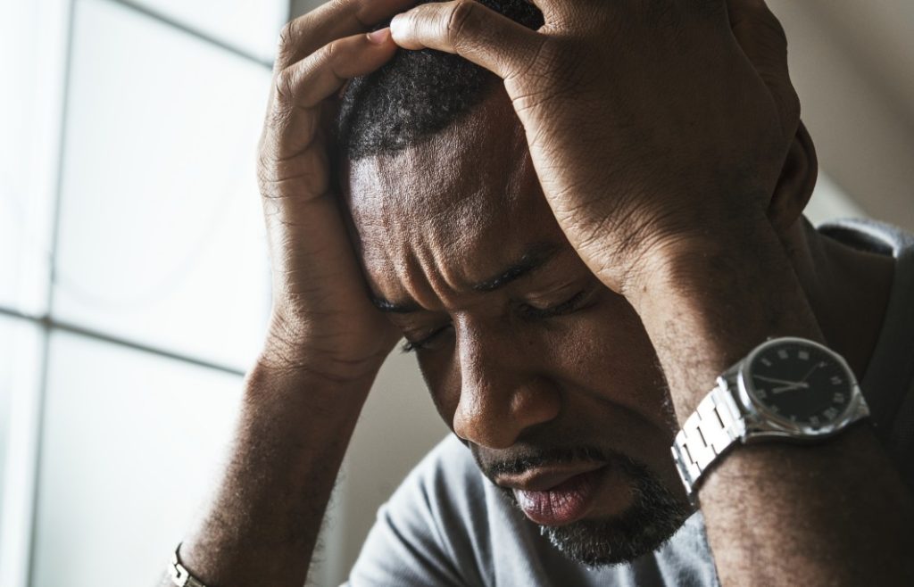 "Homem com expressão de eansiedade segurando a cabeça