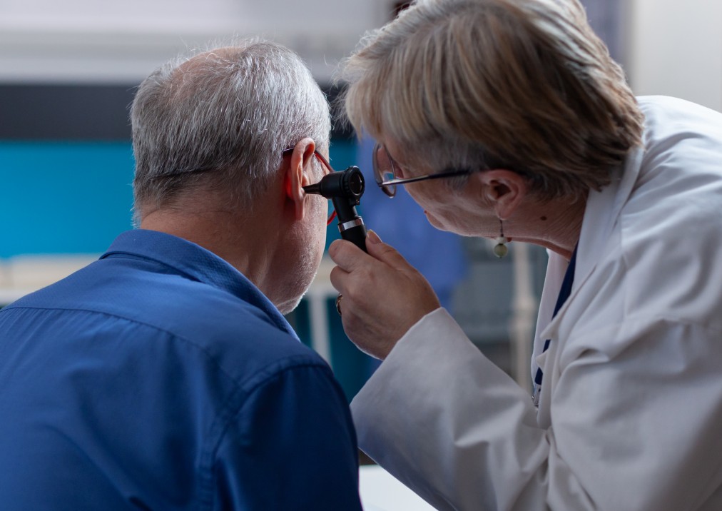 Médica examinando o ouvido de um paciente com otoscópio