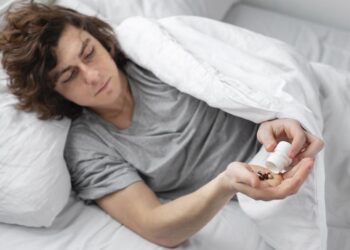 homem na cama tomando uma medicao