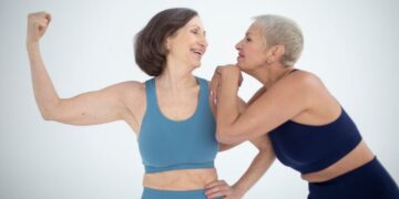 "Duas mulheres maduras sorrindo e se divertindo em roupas de treino, transmitindo vitalidade e amizade.