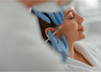 Mulher recebendo aplicação estética com seringa no rosto