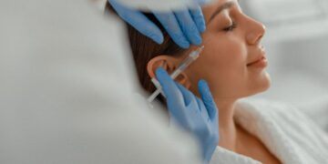 Mulher recebendo aplicação estética com seringa no rosto