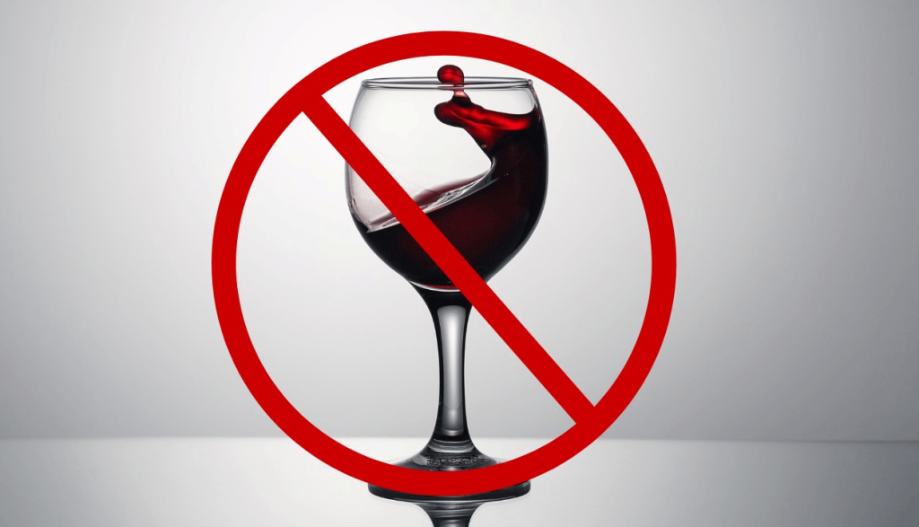 Fundo cinza. Uma taça de vinho ao centro com um símbolo de pare em cima.