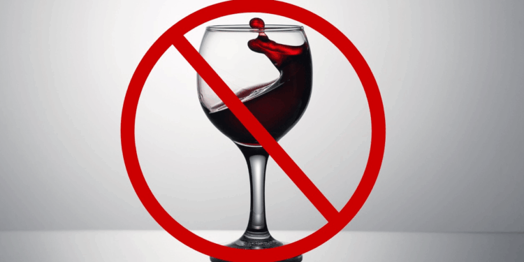 Fundo cinza. Uma taça de vinho ao centro com um símbolo de pare em cima.