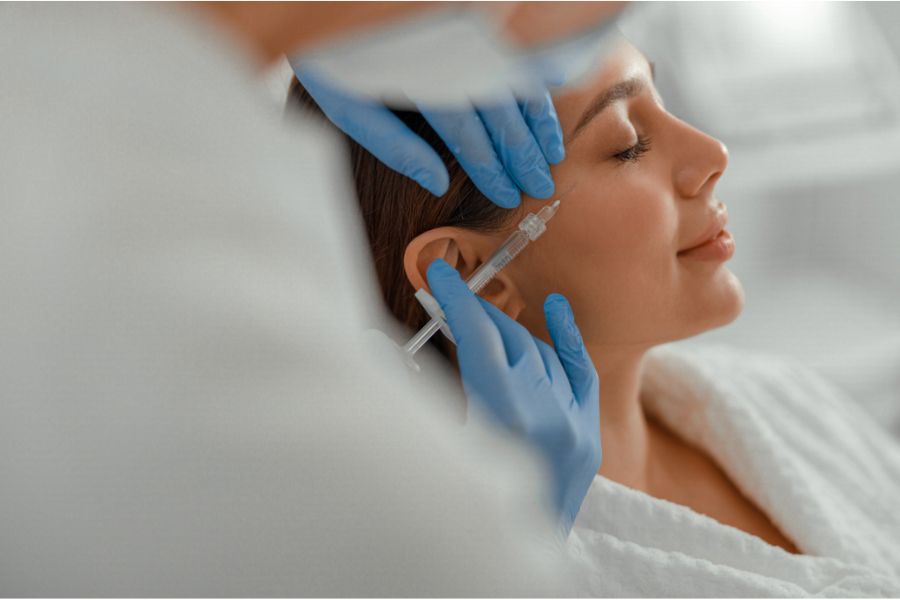 Mulher recebendo aplicação estética com seringa no rosto