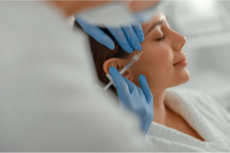 Mulher recebendo aplicação estética com seringa no rosto