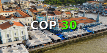 Foto aérea da cidade de Belém do Pará. Ao centro, COP 30. COP em letras brancas e o numeral 30 em verde.