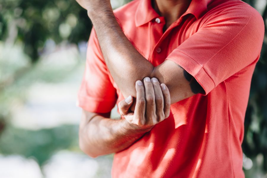 Pessoa segurando o cotovelo com sinal de dor.